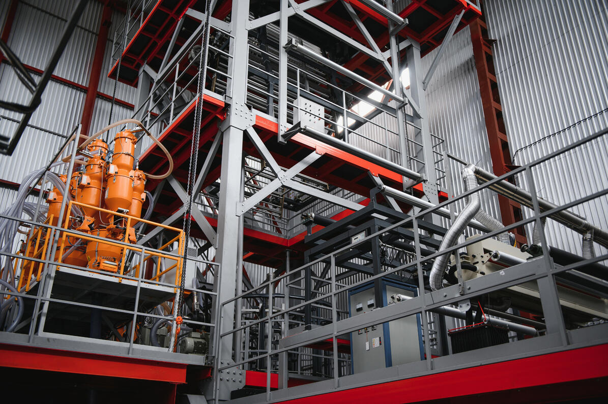 Multi-story industrial frame supporting processing machinery, platforms, and piping.