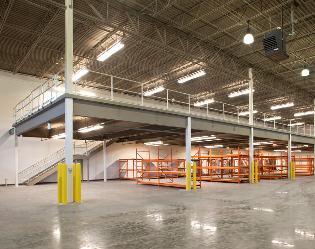 Elevated steel mezzanine system in a warehouse for storage, staging, or access.
