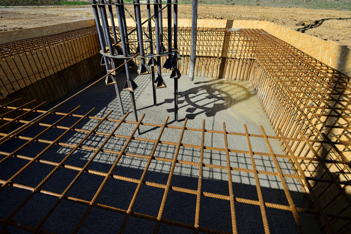 Cast-in-place concrete base slab with anchor bolts for securing mechanical and structural equipment.