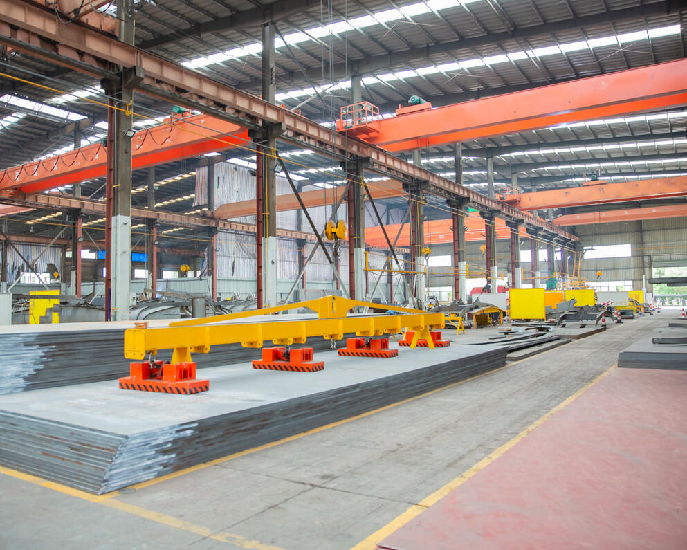 Crane-integrated portal frame structure used for lifting heavy steel plates in fabrication environments.