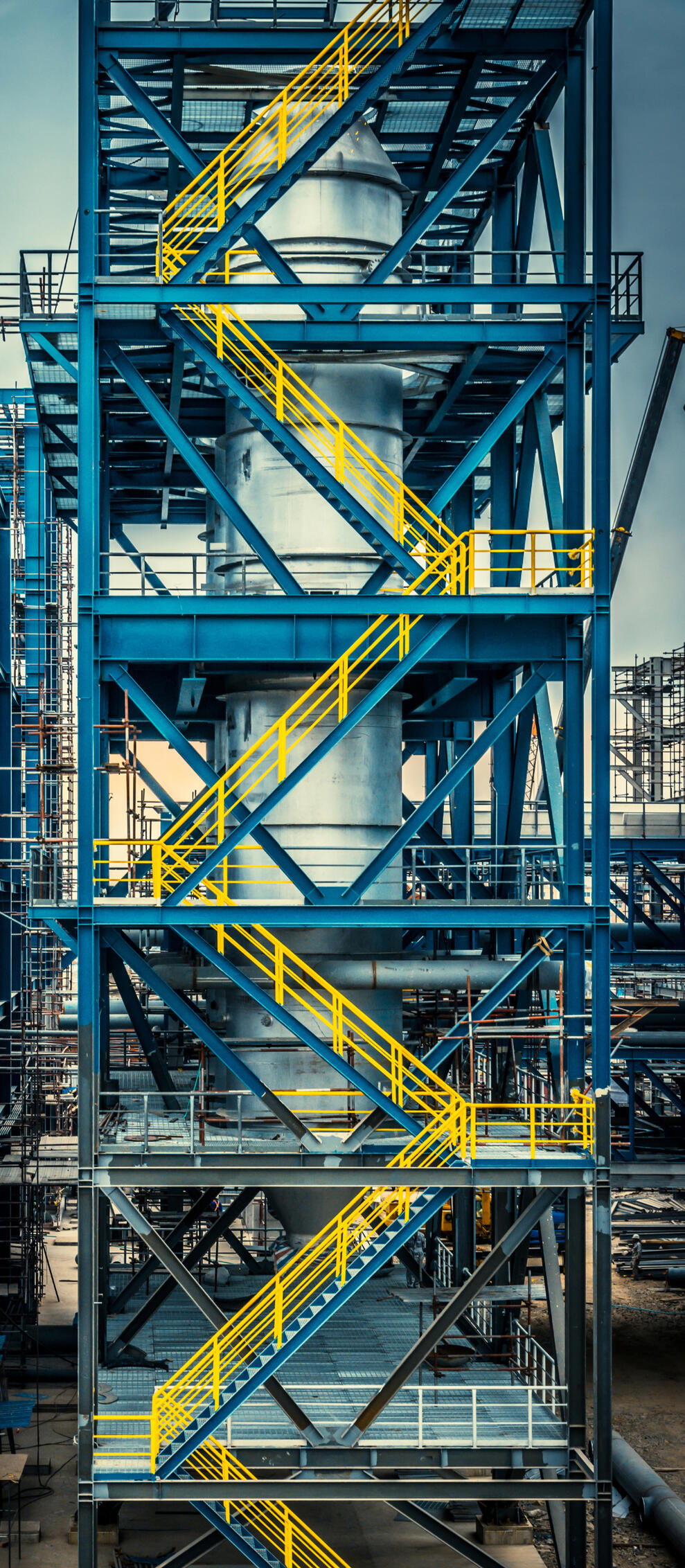 Steel-framed access tower with bracing and staircases, supporting industrial equipment.